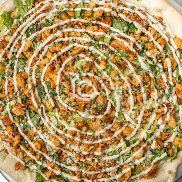 Overhead view of a Farmers Pizza chicken Caesar pizza with lettuce, chicken, and white sauce.