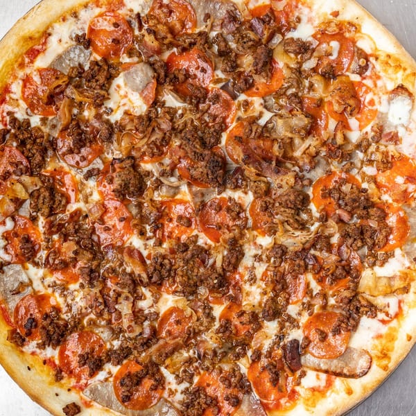 A close-up, overhead view of a Farmers Pizza with pepperoni, sausage, and ground beef.